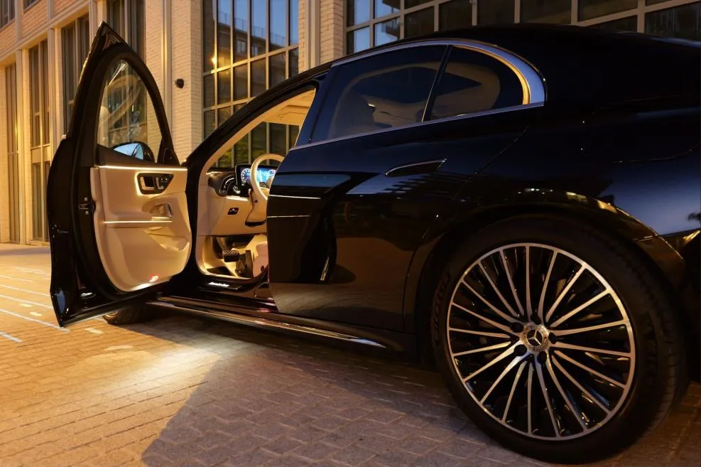 A black Mercedes-Benz sedan with its rear door open onto a cream leather cabin