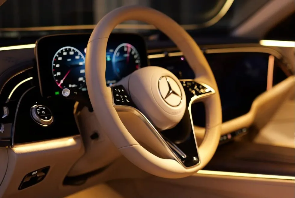 A Mercedes-Benz steering wheel and digital cockpit in cream leather